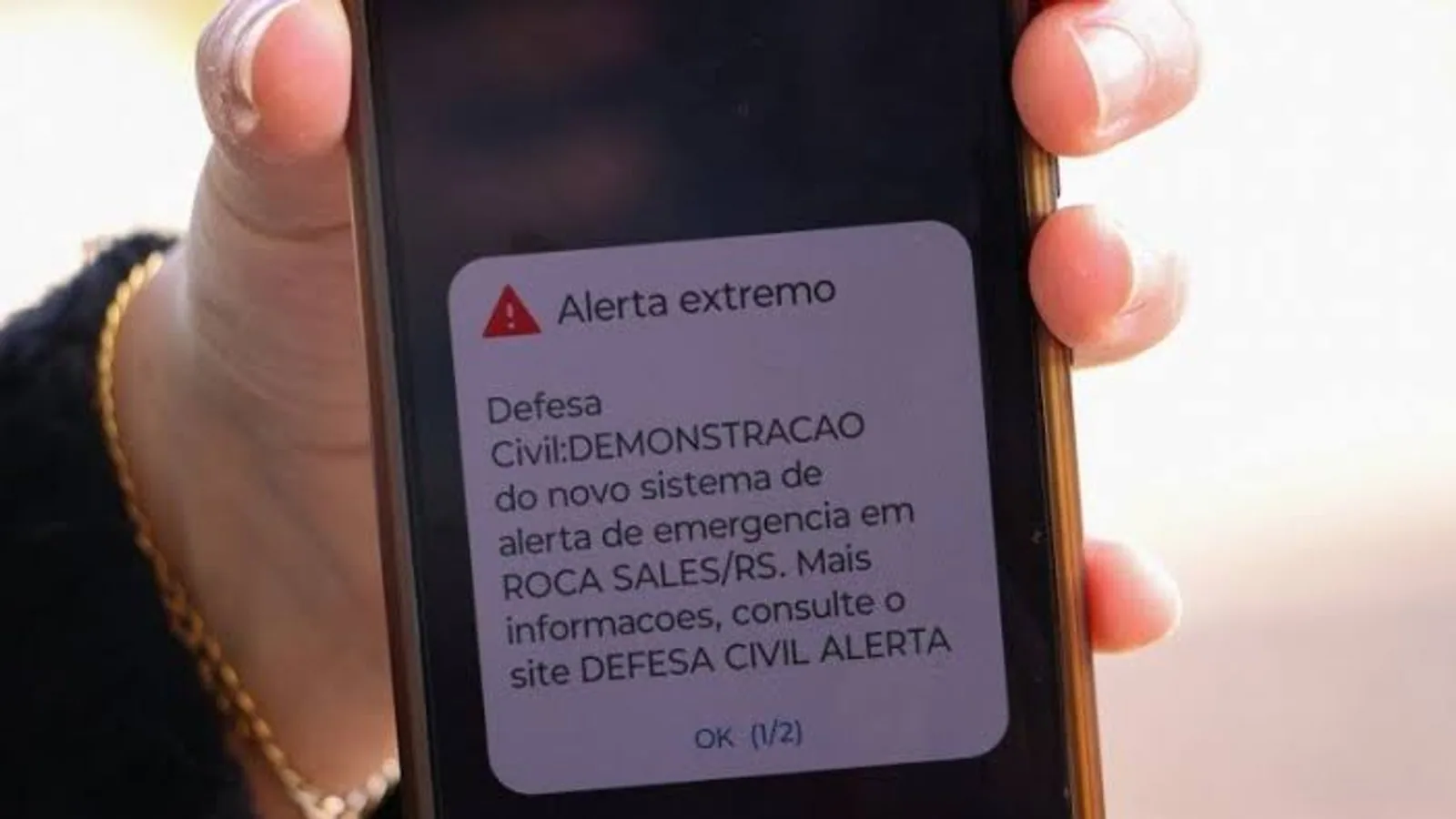 Nuvem de supercélula com rotação sobre cidade e alerta de emergência no celular
